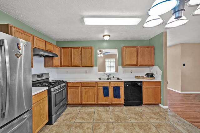12821 Donegal Way, Houston, TX 77047 - kitchen featuring stainless steel appliances, under cabinet range hood, light countertops, a textured ceiling, and brown cabinets