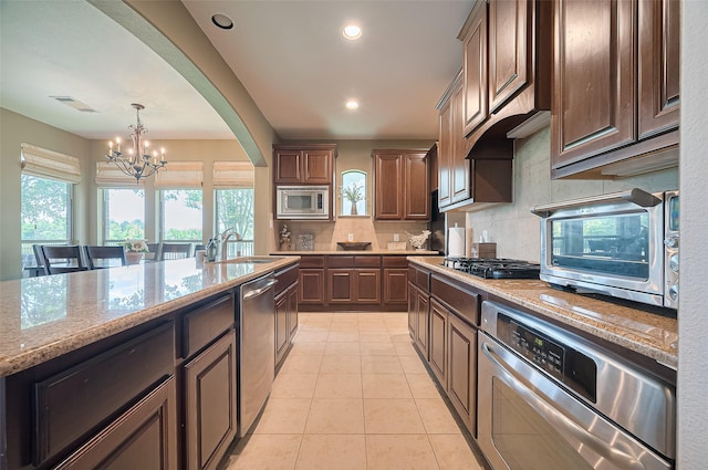 17207 Red Oak Bend Dr, Cypress, TX 77433 - kitchen featuring appliances with stainless steel finishes, a chandelier, a sink, tasteful backsplash, and light stone counters