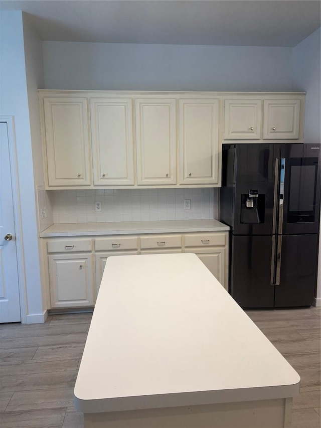 18918 Cypresswood Forest Ct, Spring, TX 77388 - kitchen featuring black fridge with ice dispenser, light wood-style flooring, white cabinets, light countertops, and a kitchen island