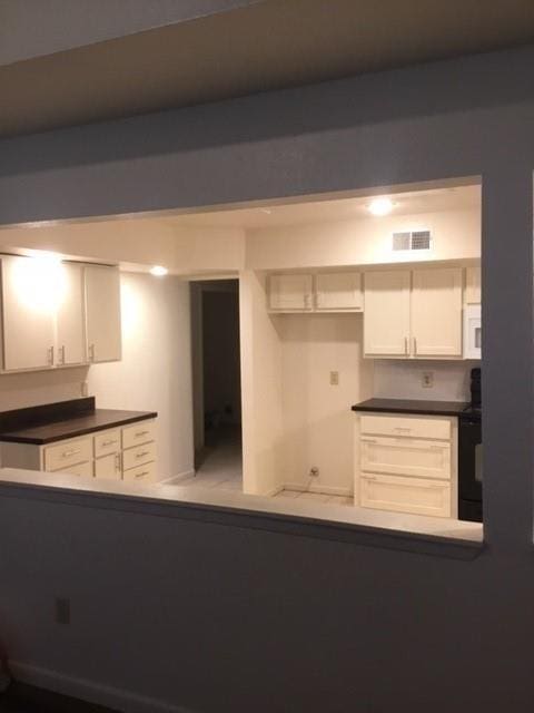 3004 Creek View Dr, Missouri City, TX 77459 - kitchen featuring white microwave, dark countertops, white cabinetry, and range