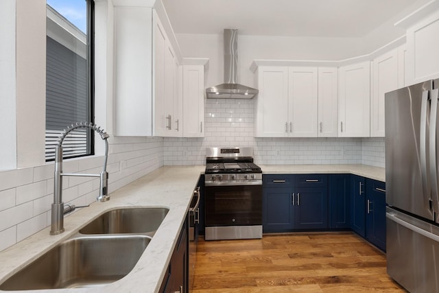 1205 Summer St Unit C, Houston, TX 77007 - kitchen with appliances with stainless steel finishes, wall chimney exhaust hood, a sink, blue cabinets, and white cabinetry
