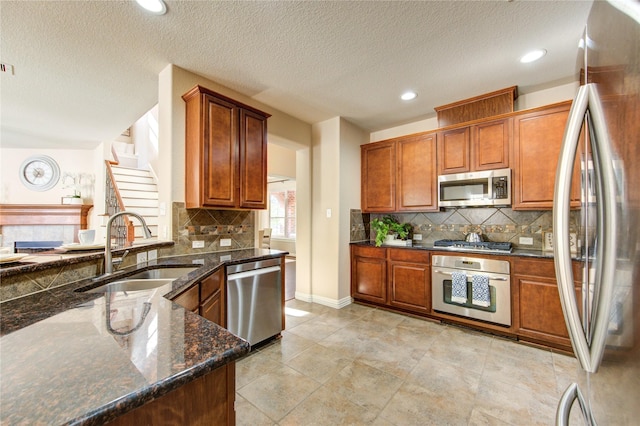 27107 Downing Park Blvd, Katy, TX 77494 - kitchen featuring stainless steel appliances, a sink, tasteful backsplash, brown cabinetry, and a textured ceiling