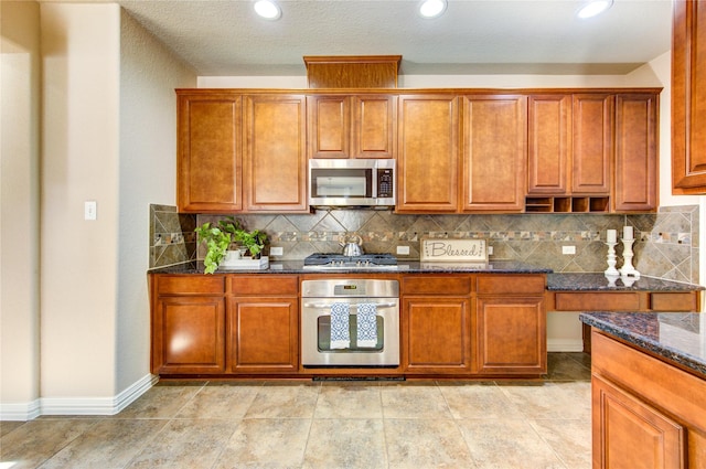 27107 Downing Park Blvd, Katy, TX 77494 - kitchen with appliances with stainless steel finishes, dark stone counters, brown cabinetry, backsplash, and recessed lighting