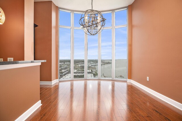4821 Nasa Pkwy Unit 12E, Pasadena, TX 77586 - unfurnished dining area with floor to ceiling windows, a chandelier, baseboards, and hardwood / wood-style flooring