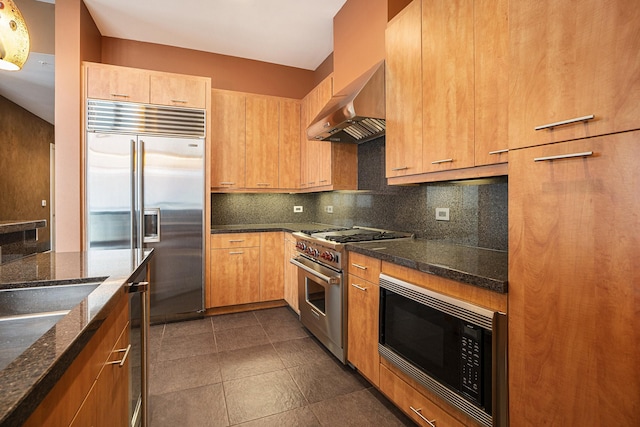 4821 Nasa Pkwy Unit 12E, Pasadena, TX 77586 - kitchen with premium appliances, ventilation hood, backsplash, dark stone countertops, and dark tile patterned flooring