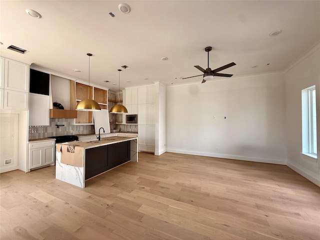 923 Fisher St Unit B, Houston, TX 77018 - kitchen featuring decorative backsplash, an island with sink, ornamental molding, light wood-type flooring, and a sink