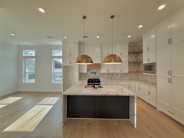 923 Fisher St Unit B, Houston, TX 77018 - kitchen with open shelves, stainless steel microwave, decorative backsplash, light wood finished floors, and white cabinets