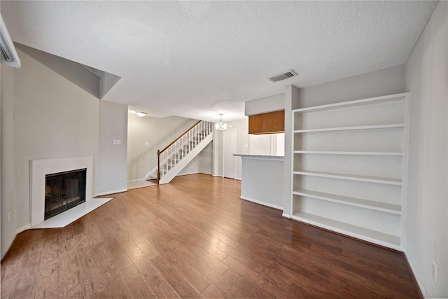2120 El Paseo St Unit 2901, Houston, TX 77054 - unfurnished living room featuring stairs, a textured ceiling, wood finished floors, a chandelier, and a fireplace with flush hearth