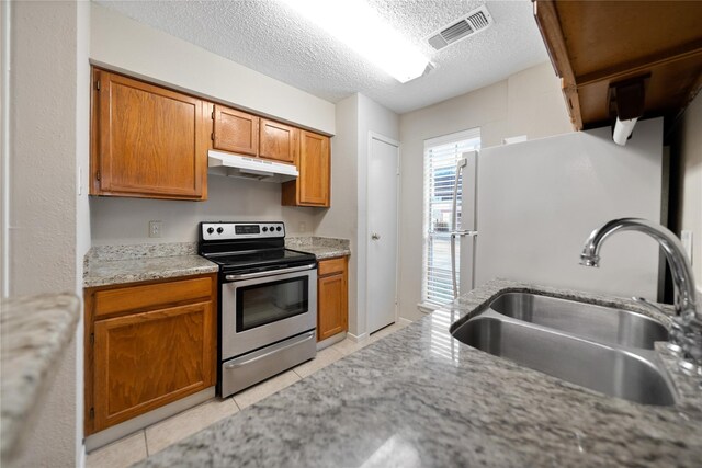 2120 El Paseo St Unit 2901, Houston, TX 77054 - kitchen with a sink, stainless steel range with electric stovetop, under cabinet range hood, light tile patterned floors, and brown cabinetry