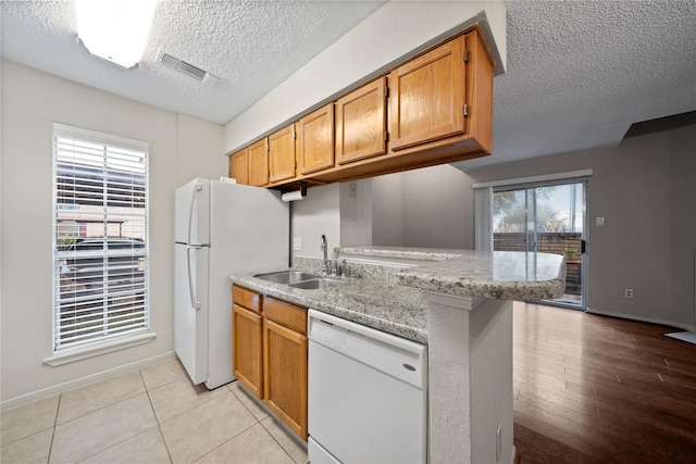 2120 El Paseo St Unit 2901, Houston, TX 77054 - kitchen with white appliances, a sink, a textured ceiling, brown cabinetry, and a peninsula