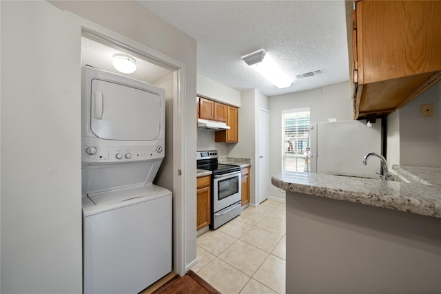 2120 El Paseo St Unit 2901, Houston, TX 77054 - kitchen featuring stainless steel electric range, stacked washer / drying machine, freestanding refrigerator, brown cabinets, and under cabinet range hood