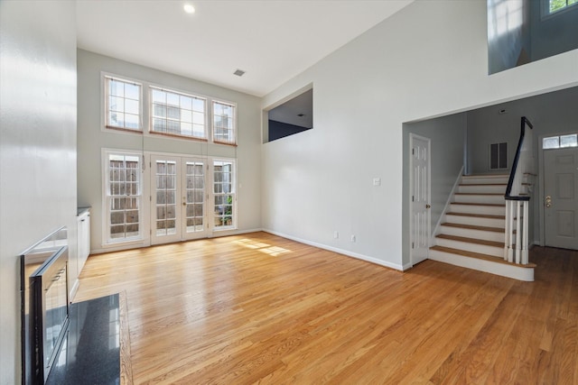 1984 Indiana St, Houston, TX 77019 - unfurnished living room featuring a high ceiling, stairs, plenty of natural light, and light wood-style floors