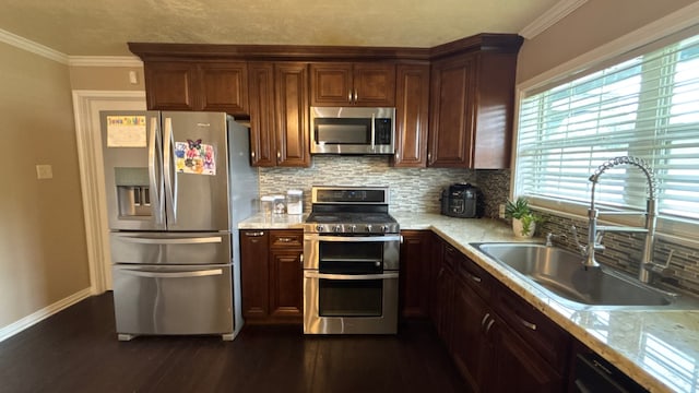 4400 Bethany St, Port Arthur, TX 77642 - kitchen with stainless steel appliances, a sink, dark wood-style flooring, decorative backsplash, and ornamental molding