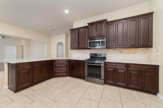 6230 Borg Breakpoint Dr, Spring, TX 77379 - kitchen with appliances with stainless steel finishes, a peninsula, backsplash, arched walkways, and recessed lighting