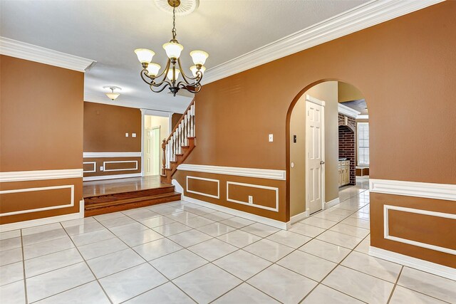 5802 Ashmere Ln, Spring, TX 77379 - unfurnished dining area with ornamental molding, light tile patterned floors, arched walkways, a chandelier, and a wainscoted wall