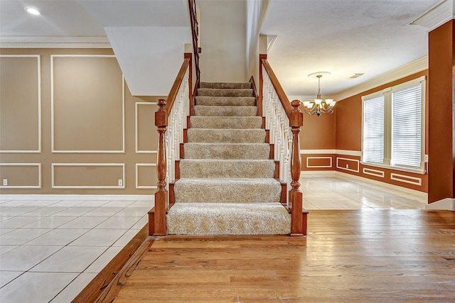 5802 Ashmere Ln, Spring, TX 77379 - staircase with a decorative wall, crown molding, wood finished floors, a chandelier, and wainscoting