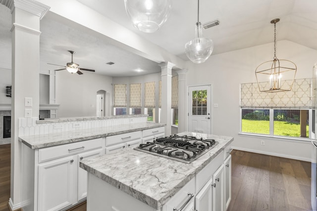 10906 Bernalda Cir, Richmond, TX 77406 - kitchen with stainless steel gas stovetop, decorative columns, dark wood-style floors, a center island, and backsplash