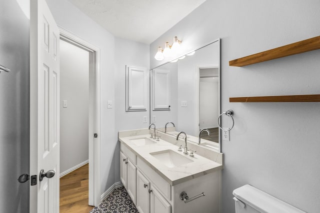 10906 Bernalda Cir, Richmond, TX 77406 - bathroom with toilet, double vanity, wood finished floors, and baseboards