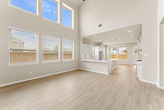 2218 Elm Rdg, Tomball, TX 77375 - unfurnished living room featuring light wood-type flooring, a towering ceiling, baseboards, and a sink