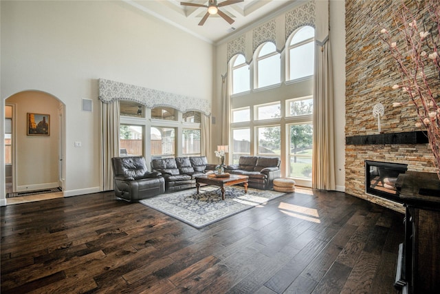 2515 Rainflower Meadow Ln, Katy, TX 77494 - living room with a high ceiling, ceiling fan, arched walkways, dark wood-style flooring, and a stone fireplace