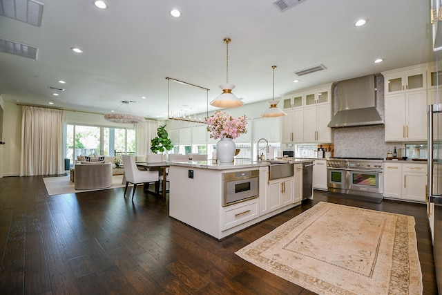 802 W 30th St, Houston, TX 77018 - kitchen with appliances with stainless steel finishes, wall chimney exhaust hood, a sink, backsplash, and white cabinetry
