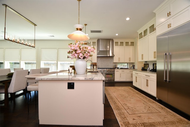 802 W 30th St, Houston, TX 77018 - kitchen featuring high end appliances, wall chimney exhaust hood, a center island with sink, white cabinetry, and recessed lighting