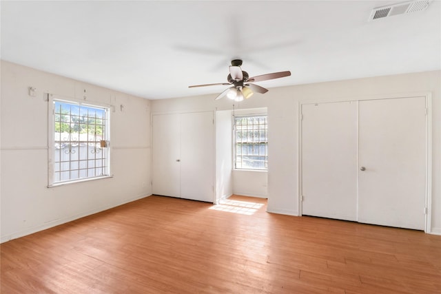 7547 Touchstone St, Houston, TX 77028 - unfurnished bedroom featuring multiple closets, multiple windows, light wood-type flooring, and baseboards