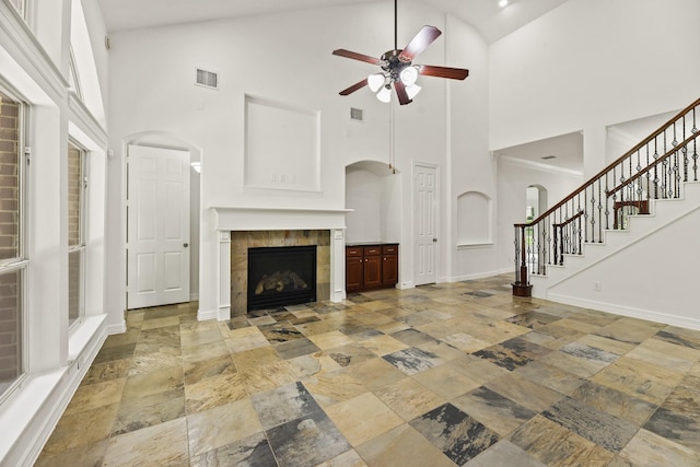 512 Cherry Hills Dr, Huntsville, TX 77340 - unfurnished living room featuring stone tile floors, a ceiling fan, high vaulted ceiling, a fireplace, and stairs