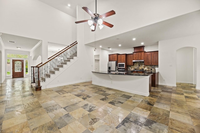 512 Cherry Hills Dr, Huntsville, TX 77340 - kitchen with arched walkways, stainless steel appliances, stone tile floors, baseboards, and a towering ceiling