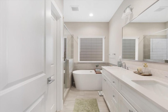 8307 Brecha Ln, Houston, TX 77055 - bathroom featuring a shower stall, double vanity, a freestanding tub, tile walls, and recessed lighting