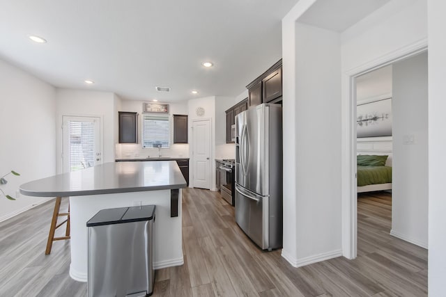 15511 Bosque Valley Ct, Cypress, TX 77433 - kitchen with stainless steel appliances, a center island, dark brown cabinets, light wood-style flooring, and recessed lighting