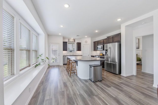 15511 Bosque Valley Ct, Cypress, TX 77433 - kitchen with stainless steel appliances, a kitchen island, light wood-type flooring, dark brown cabinets, and recessed lighting