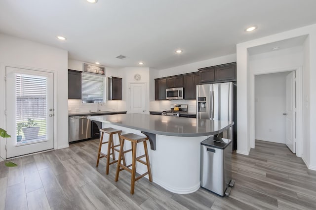 15511 Bosque Valley Ct, Cypress, TX 77433 - kitchen with appliances with stainless steel finishes, dark brown cabinetry, light wood-style flooring, a kitchen bar, and recessed lighting