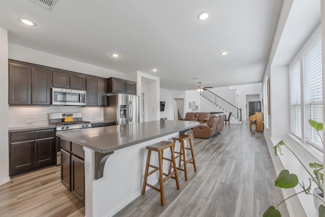 15511 Bosque Valley Ct, Cypress, TX 77433 - kitchen with appliances with stainless steel finishes, dark brown cabinets, light wood-type flooring, a kitchen breakfast bar, and a center island
