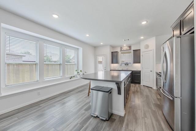 15511 Bosque Valley Ct, Cypress, TX 77433 - kitchen featuring stainless steel appliances, a sink, a kitchen island, light wood-style flooring, and a kitchen breakfast bar