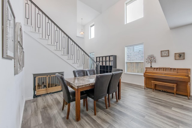 15511 Bosque Valley Ct, Cypress, TX 77433 - dining room featuring wood finished floors, a towering ceiling, healthy amount of natural light, and stairs