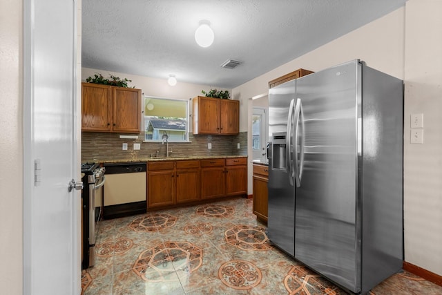 16338 N Glade, Houston, TX 77073 - kitchen featuring stainless steel appliances, brown cabinetry, decorative backsplash, a sink, and a textured ceiling