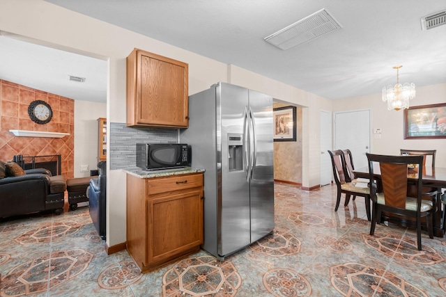 16338 N Glade, Houston, TX 77073 - kitchen with stainless steel fridge with ice dispenser, black microwave, a chandelier, brown cabinets, and baseboards