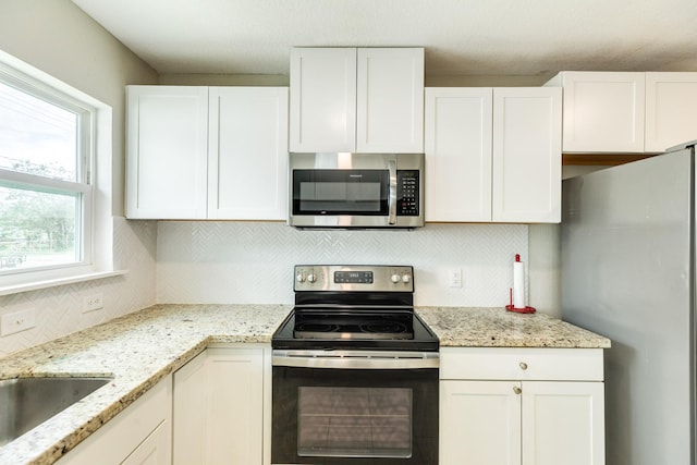 1502 W 9th St, Freeport, TX 77541 - kitchen featuring appliances with stainless steel finishes, decorative backsplash, white cabinetry, light stone counters, and a sink