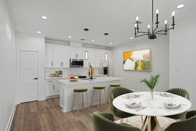 8417 Venus St Unit A B, Houston, TX 77088 - kitchen featuring stainless steel microwave, white fridge with ice dispenser, a sink, a kitchen island with sink, and wood finished floors