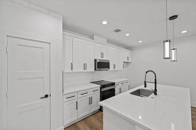 8417 Venus St Unit A B, Houston, TX 77088 - kitchen featuring stainless steel microwave, a sink, black range with electric cooktop, wood finished floors, and white cabinets
