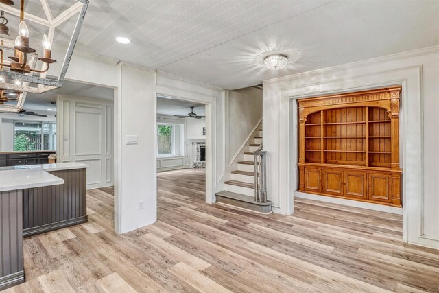 12906 Ivyforest Dr, Cypress, TX 77429 - unfurnished living room with crown molding, ceiling fan, stairs, light wood-style floors, and a fireplace with raised hearth