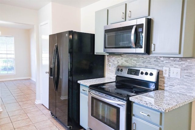 18389 Ten Oaks Ct, Porter, TX 77365 - kitchen with appliances with stainless steel finishes, light tile patterned floors, tasteful backsplash, baseboards, and light stone counters