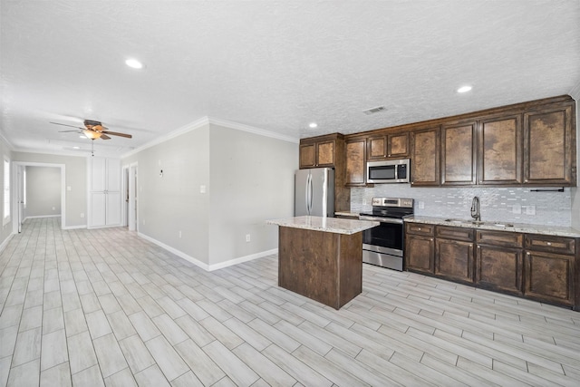 7941 Goode St, Houston, TX 77012 - kitchen with appliances with stainless steel finishes, a sink, baseboards, backsplash, and a center island