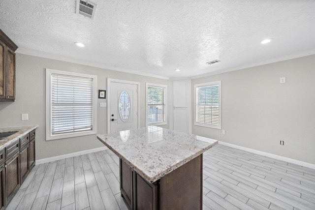 7941 Goode St, Houston, TX 77012 - kitchen featuring wood tiled floors, crown molding, a kitchen island, baseboards, and a textured ceiling