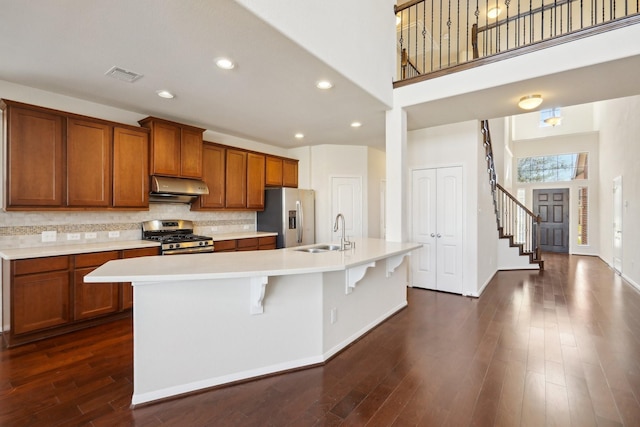 2813 Bottiglia Way, League City, TX 77573 - kitchen with stainless steel appliances, under cabinet range hood, a sink, brown cabinetry, and recessed lighting