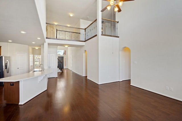 2813 Bottiglia Way, League City, TX 77573 - unfurnished living room featuring arched walkways, ceiling fan, a sink, dark wood-type flooring, and a high ceiling