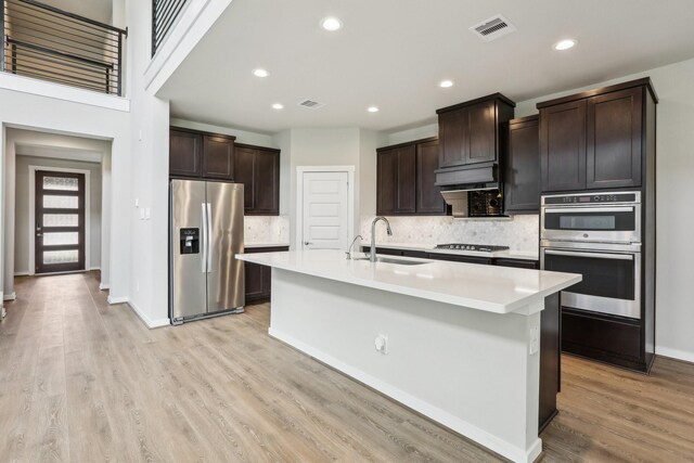 29211 Pikes Peak Dr, Katy, TX 77494 - kitchen with stainless steel appliances, a sink, tasteful backsplash, light countertops, and dark brown cabinetry