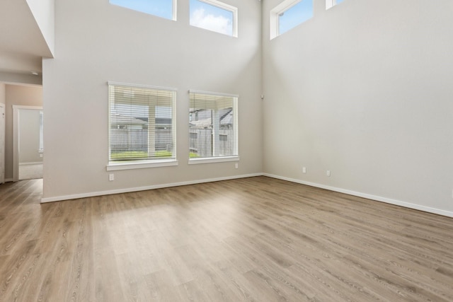 29211 Pikes Peak Dr, Katy, TX 77494 - unfurnished living room featuring a towering ceiling, wood finished floors, and baseboards