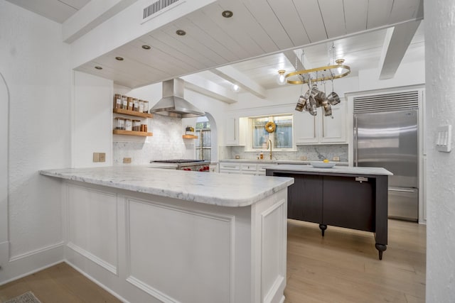 11 Twin Circle Dr, Houston, TX 77042 - kitchen featuring built in refrigerator, island exhaust hood, decorative backsplash, light wood finished floors, and arched walkways
